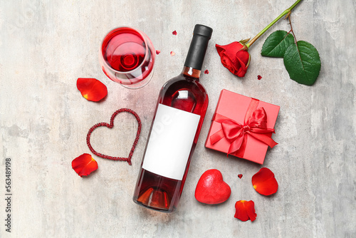 Composition with glass of wine, bottle, rose flower and gift on grey grunge background. Valentine's Day celebration