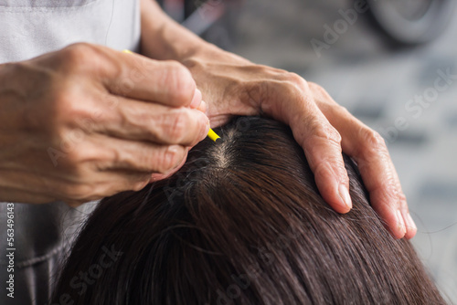 Close-up Woman plucking out gray hair with tweezers.