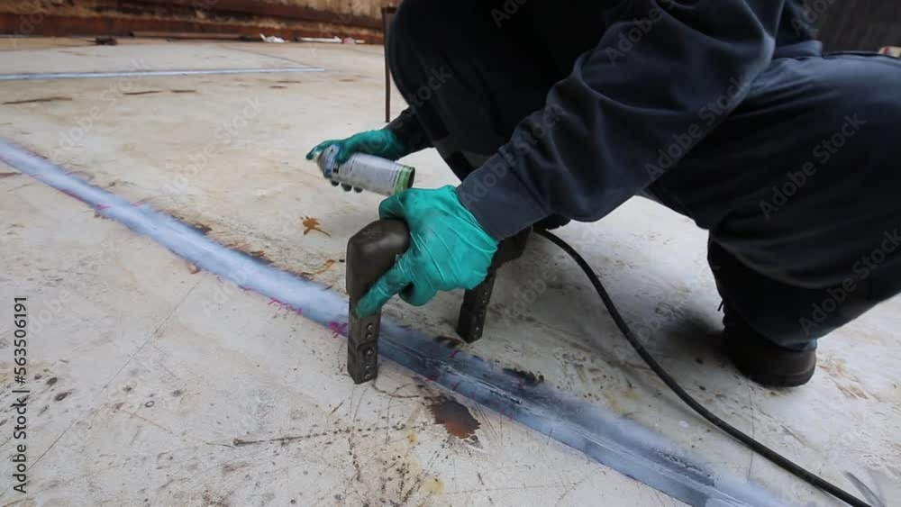 Male worker test steel tank butt weld carbon bottom plate of storage tank oil background white contrast of magnetic field test.