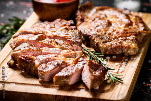 Slices of grilled steak pork on a wooden cutting board. 