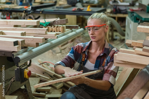 young carpenter woman wear uniform and goggles choose the size and quality wood used for work. craftsman professional concept. woodworking industry. © eakgrungenerd