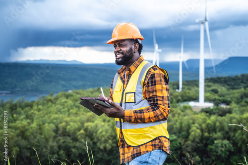 Portrait of engineer African American man working with laptop in wind turbine farm. © Jirus