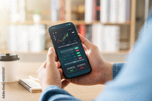 Concept of value investor and trader, businessman using smart phone application to invest in stock market, technical price charts and indicators, global stock and asset investment.