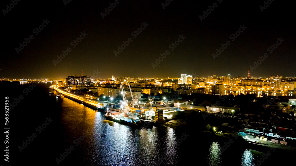 Astrakhan, Russia. Port cranes unload dry cargo. Working port. Embankment of the Volga River. Night city lights, Aerial View