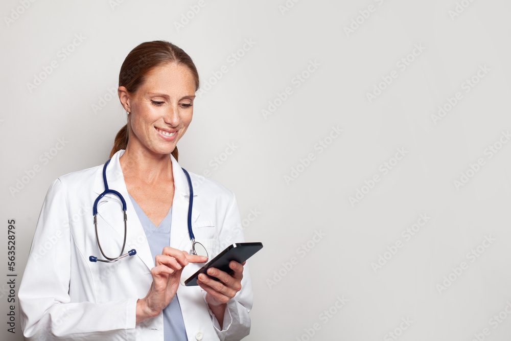 Cheerful confident happy mature mid adult woman doctor medical worker holding smartphone in her hand, female portrait Cheerful confident happy mature mid adult woman doctor medical worker holding smartphone in her hand, female portrait