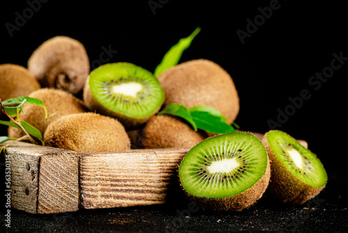 Ripe kiwi with leaves on a wooden tray. 