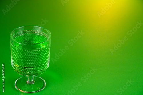 glass filled with emerald spirit cocktail with green background to be drunk at celebrations for St Patrick's day. Irish holiday is popular drinking event when people party and drink excessively