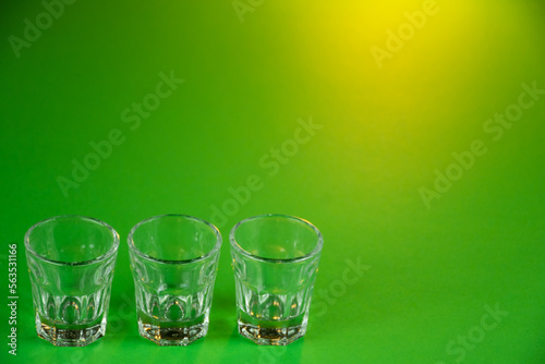Empty shot glasses lined up against emerald green theme background waiting to be filled and slammed in celebrations for St Patrick's day. Irish holiday is popular drinking event when people party