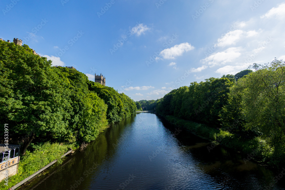 Durham England: 2022-06-07: Durham Cathedral on the River Wear during sunny summer day with lush green trees and blue sky
