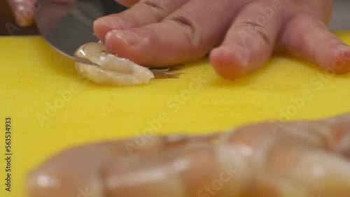 The chef cuts srimps on a board with a knife photo