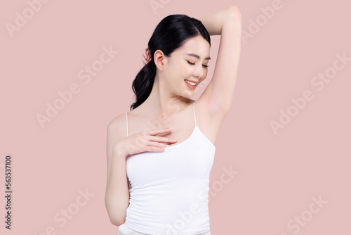 Beautiful young Asian woman lifting hand up to shows off clean and clear armpit or underarms isolated on pink background, Smooth and freshness armpit concept. photo