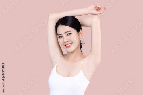 Beautiful young Asian woman lifting hand up to shows off clean and clear armpit or underarms isolated on pink background, Smooth and freshness armpit concept.