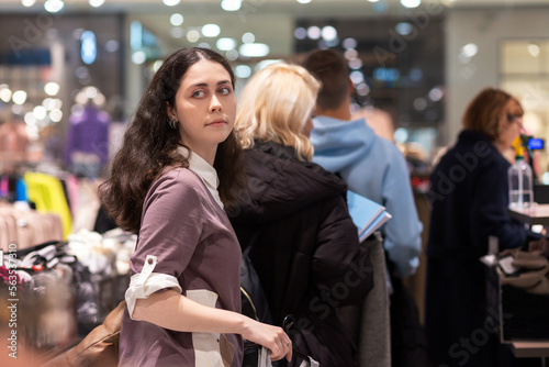 Fotografia Portrait of young Caucasian woman looking back and standing in store queue to pay for purchase