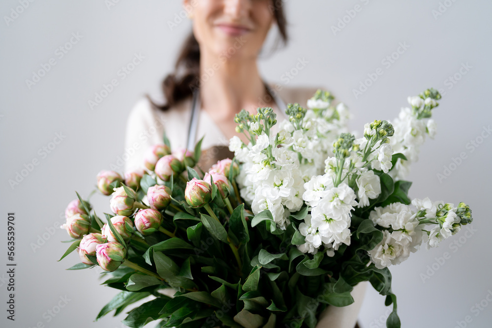 WOMAN florist EMBRACING a bunch of white and pink flowers on white background indoors WOMAN florist EMBRACING a bunch of white and pink flowers on white background indoors