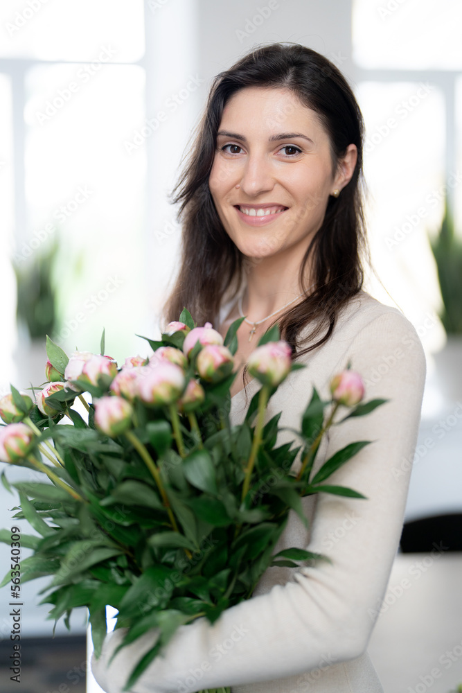Positive woman holding a huge bouquet of flowers in her office. Birthday present smile. Positive woman holding a huge bouquet of flowers in her office. Birthday present smile.