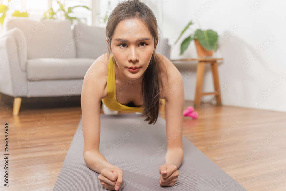 Beautiful fitness asian young woman, girl wearing sportswear training strength muscles workout, exercise training on carpet in living room at home for healthy body strong athletic fit active lifestyle Beautiful fitness asian young woman, girl wearing sportswear training strength muscles workout, exercise training on carpet in living room at home for healthy body strong athletic fit active lifestyle