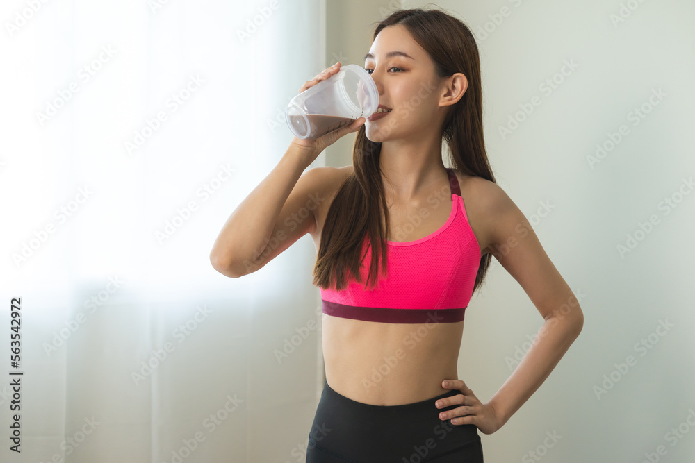 Diet meal replacement for weight loss, happy asian young woman, girl in sportswear, hand in holding protein shake bottle for drink supplement for muscle after workout at home. Healthy body care person Diet meal replacement for weight loss, happy asian young woman, girl in sportswear, hand in holding protein shake bottle for drink supplement for muscle after workout at home. Healthy body care person