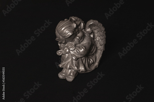 White angel statue with wings on a black background © Edite