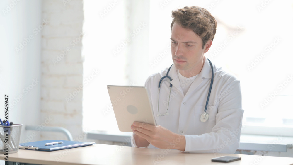 Young Doctor Browsing Internet on Tablet in Clinic Young Doctor Browsing Internet on Tablet in Clinic