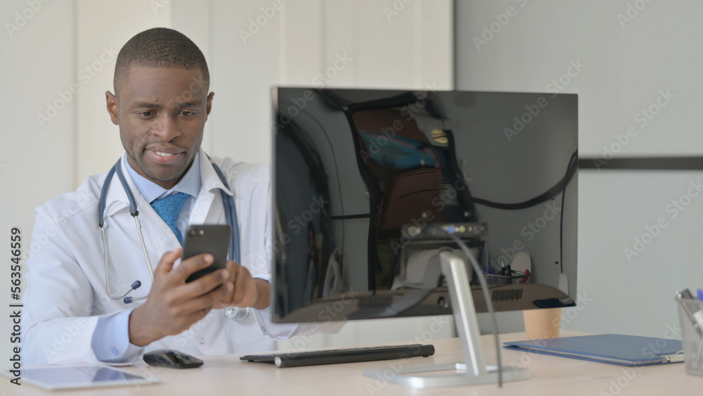 African Doctor Browsing Smartphone at Work in Clinic African Doctor Browsing Smartphone at Work in Clinic