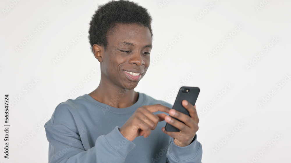 Young African Man Browsing Smartphone on White Background Young African Man Browsing Smartphone on White Background