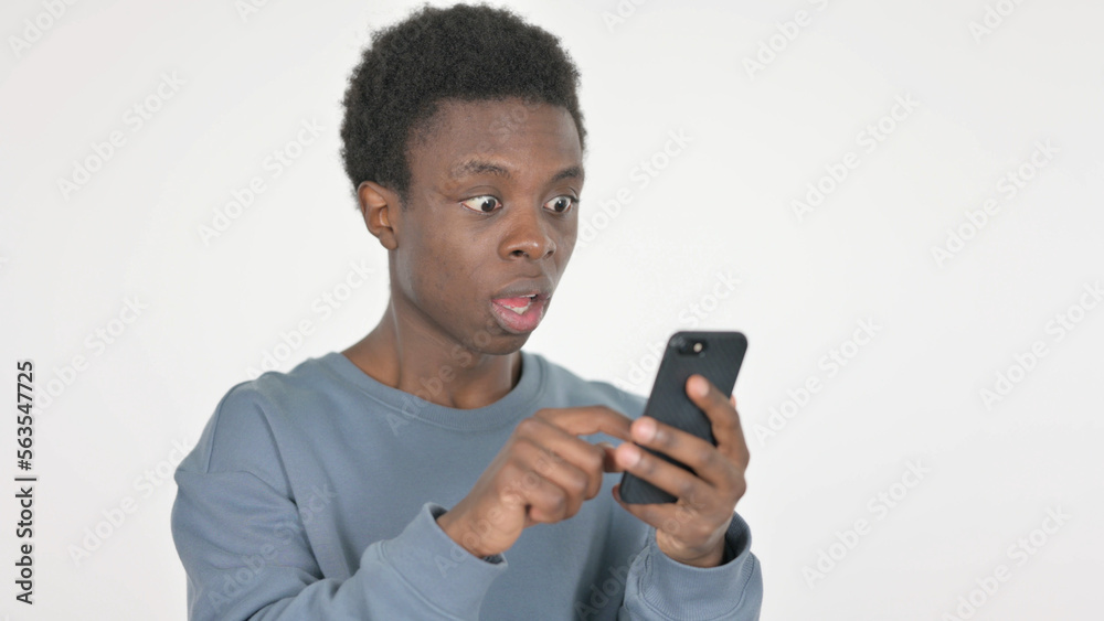 Young African Man Upset by Loss on Smartphone on White Background Young African Man Upset by Loss on Smartphone on White Background