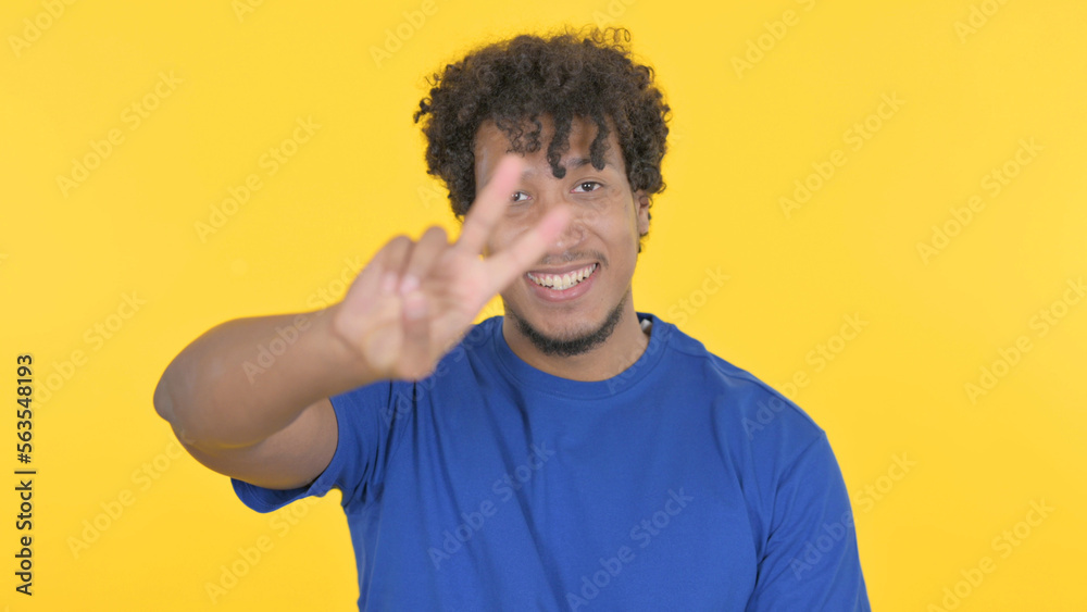 African Man with Victory Sign on Yellow Background African Man with Victory Sign on Yellow Background