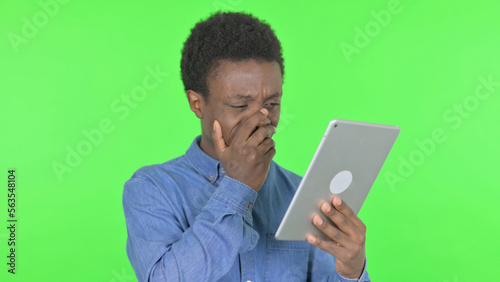 Young African Man with Loss on Tablet on Green Background