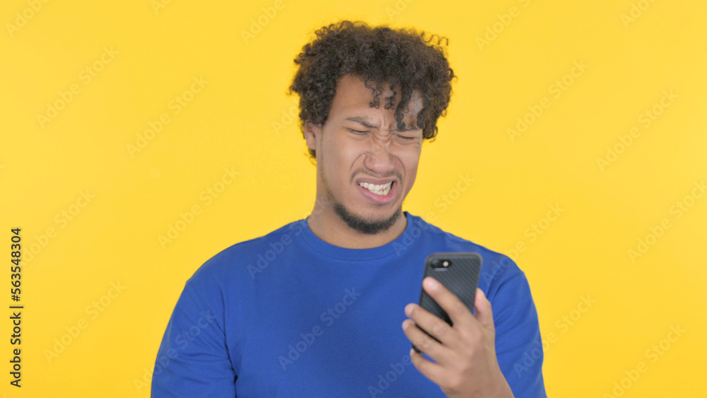 African Man Loss on Smartphone on Yellow Background African Man Loss on Smartphone on Yellow Background