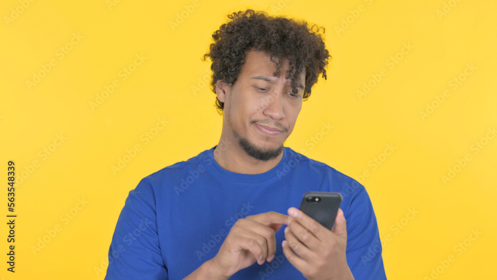 African Man Browsing Smartphone on Yellow Background African Man Browsing Smartphone on Yellow Background