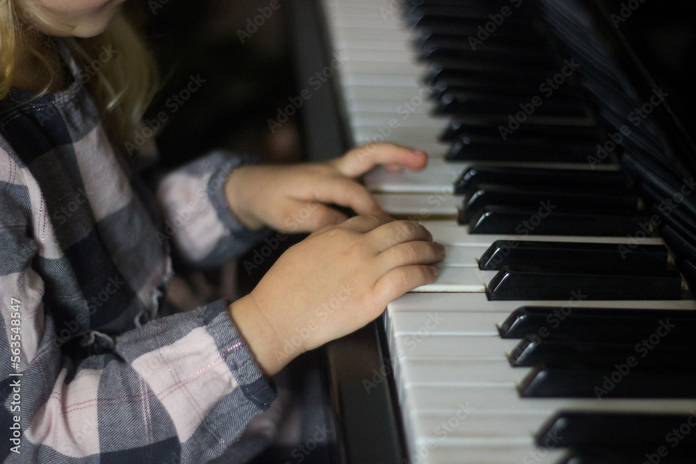 Obraz premium Little girl play piano,kids hands on piano keyboard close up,homeschooling,musical education.Growing talented child.Daily routine for toddler,side view of childs hands and piano,unfocused
