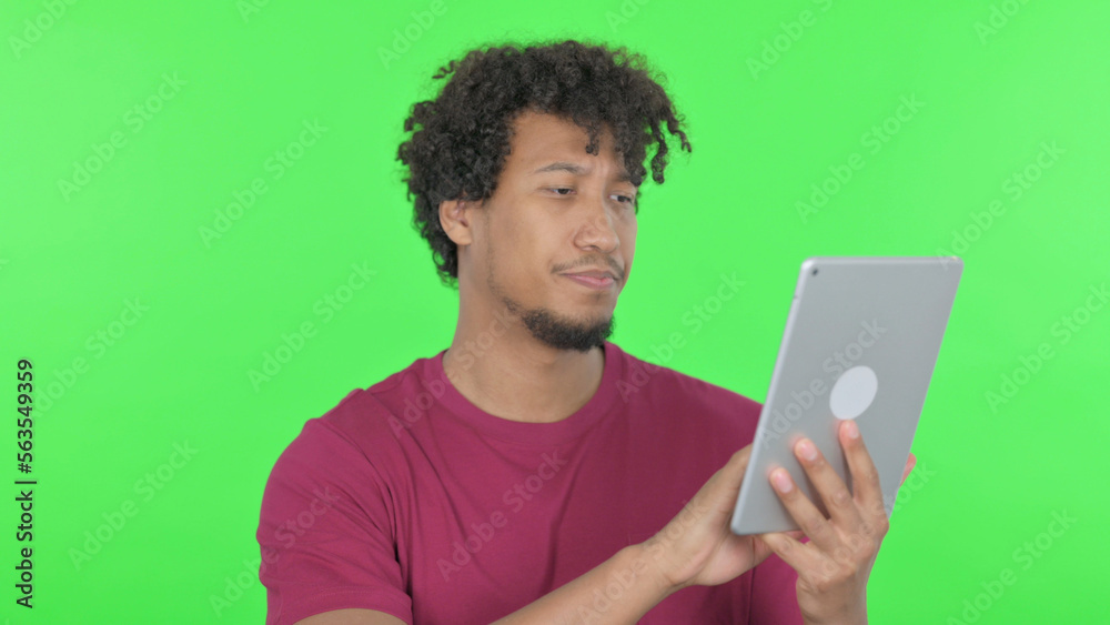 African Man using Digital Tablet on Green Background