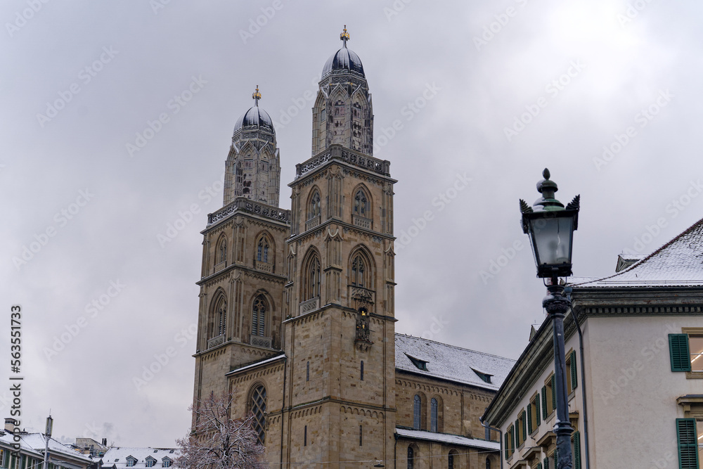 Snow covered church tower of protestant church Great Minster at the medieval old town of Zürich on a snowy gray clouded alte autumn day. Photo taken December 16th, 2022, Zurich, Switzerland.
