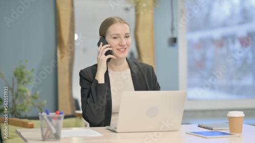 Businesswoman Talking on Phone while using Laptop