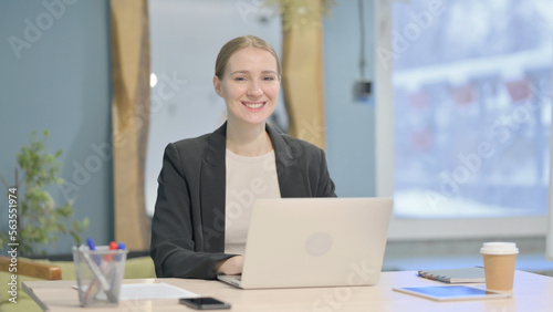 Businesswoman Smiling at Camera while using Laptop