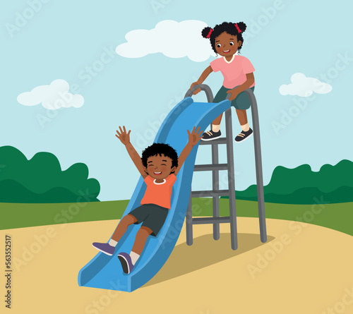 Cute little African kids boy and girl having fun on slide in playground at the park