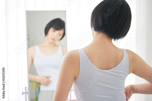 鏡を見て体型をチェックする女性