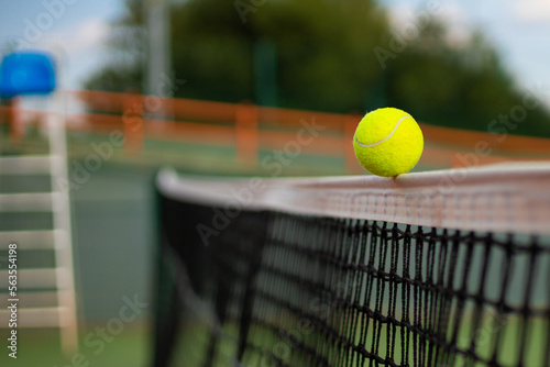 Bright greenish yellow tennis ball hitting the net. © ty