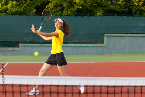 Professional equipped female tennis player beating hard the tennis ball with racquet. © ty