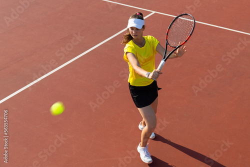 Professional equipped female tennis player beating hard the tennis ball with racquet. Top view.