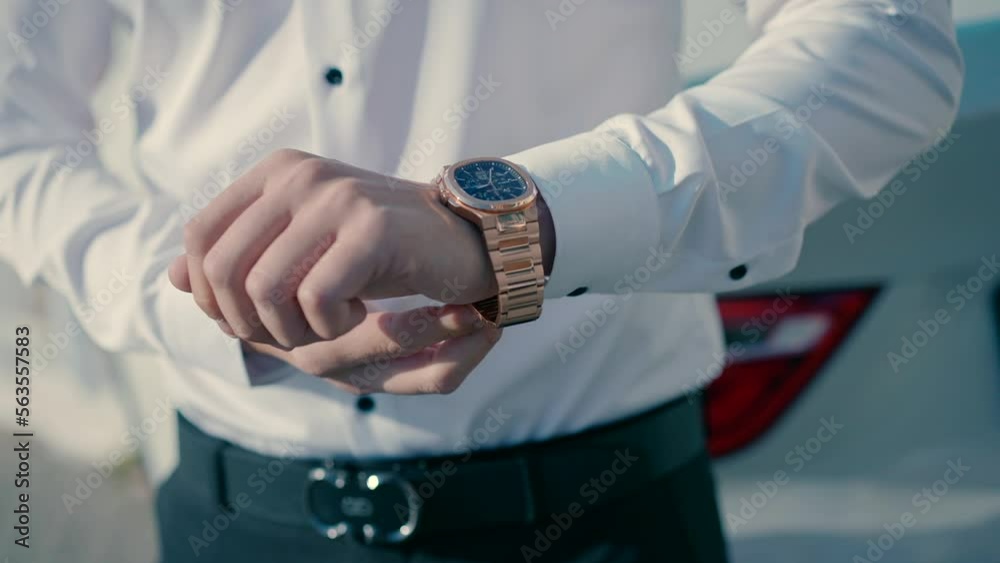 A man wearing an elegant white shirt closes the gold watch on his arm. Close-up visado slow motion shot.