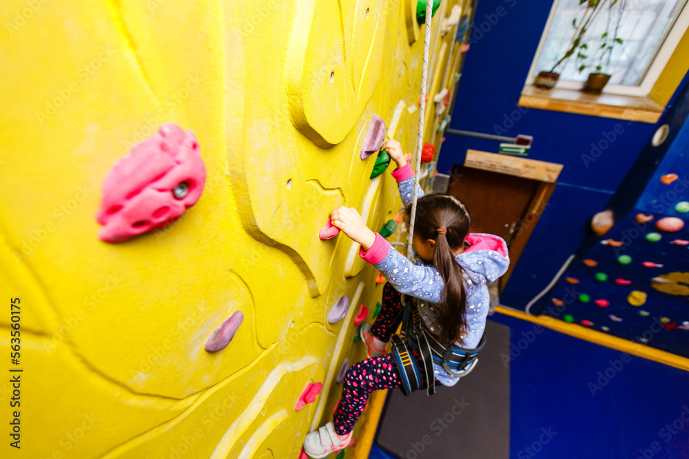 Obraz premium Little Girl Climbing Rock Wall