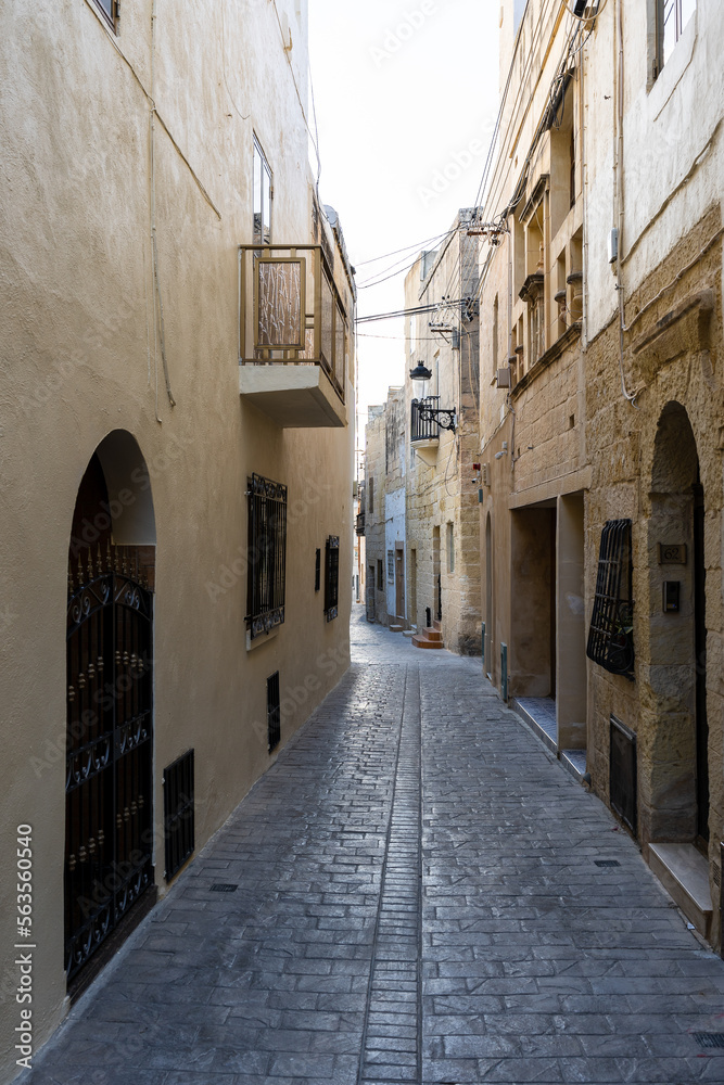 Fototapeta premium Typical narrow street with an ancient stone buildings in Mdina