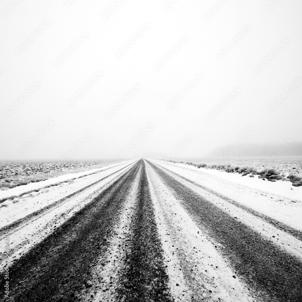 Naklejka premium Small gravel road at foggy winter day at Ypäjä, Finland.