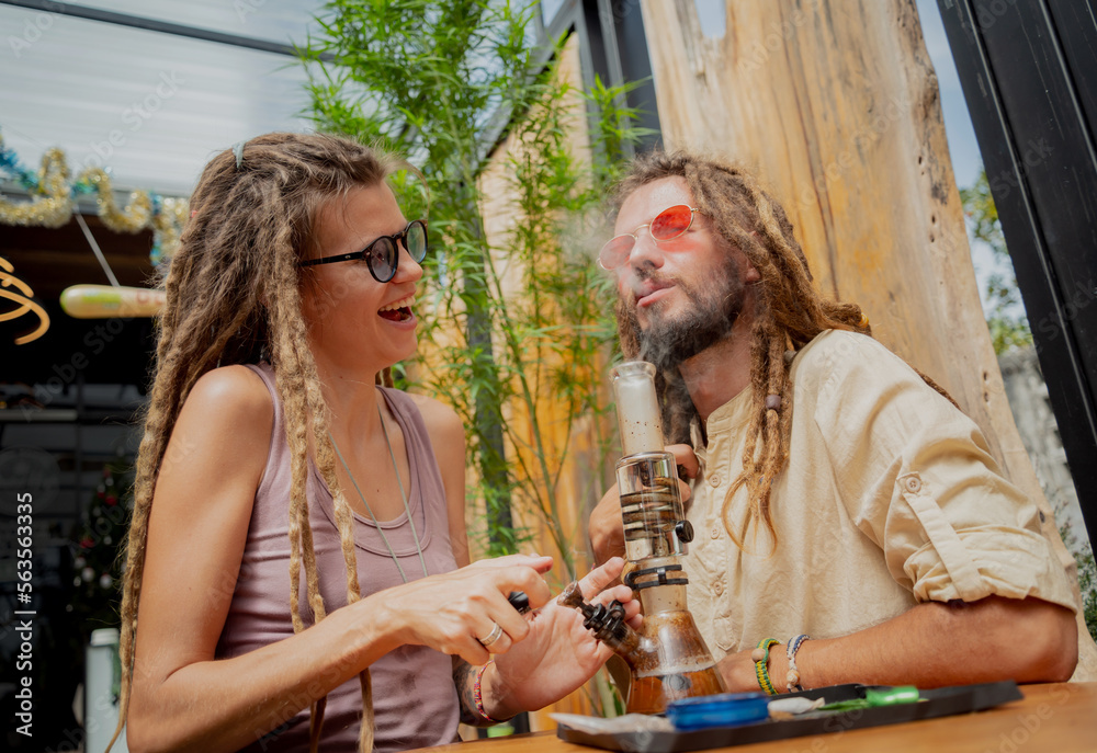 Hippie style couple smoking medical marijuana using a bong