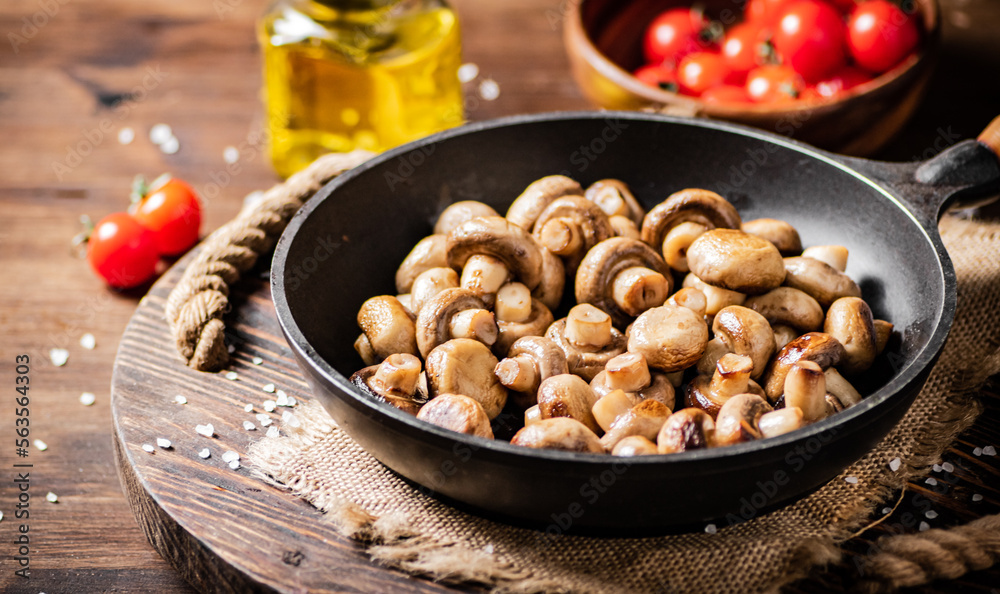 Frying pan with fried mushrooms on a wooden tray. Frying pan with fried mushrooms on a wooden tray.