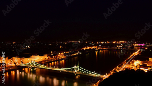 the Liberty bridge in Budapest. aerial night view. brightly illuminated steel structure. reflection on water. tourism and travel concept. transportation and design. evening lights over the Danube.