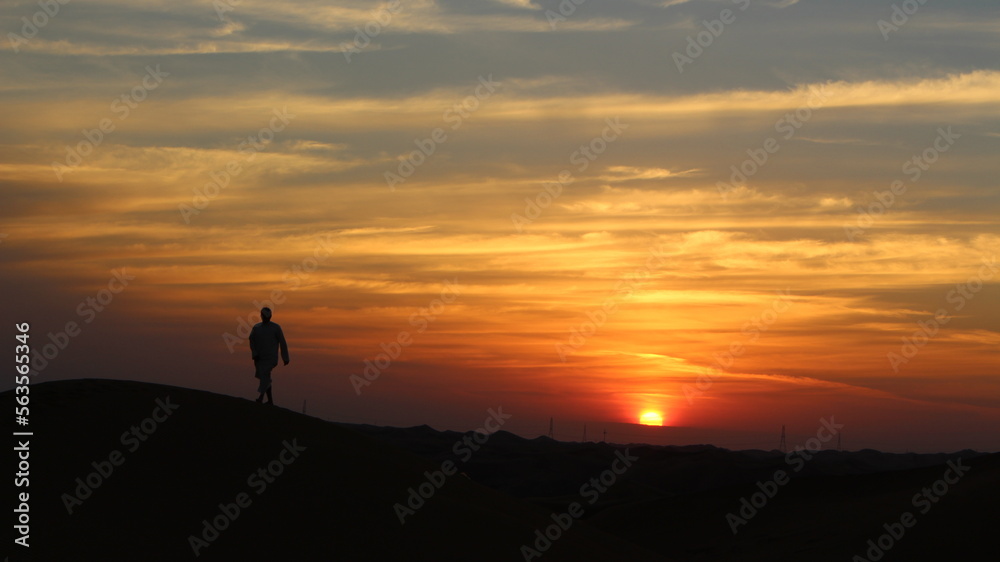 silhouette of a person on sand dunes during sunset