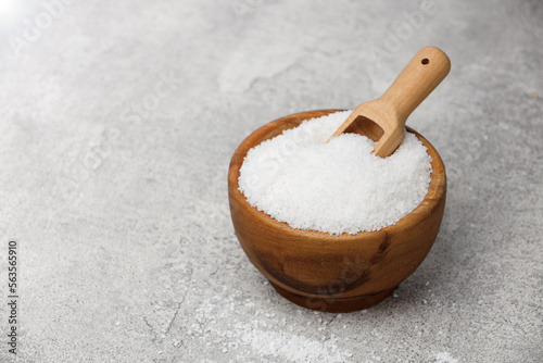 Fototapeta Coarse salt in a wooden bowl with spoon on a stone kitchen table.