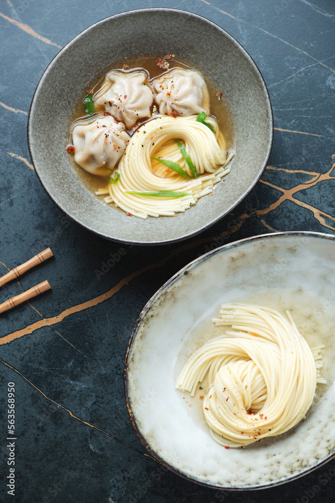 Asian wonton soup with egg noodles on a dark-olive marble background, vertical shot, high angle view Asian wonton soup with egg noodles on a dark-olive marble background, vertical shot, high angle view